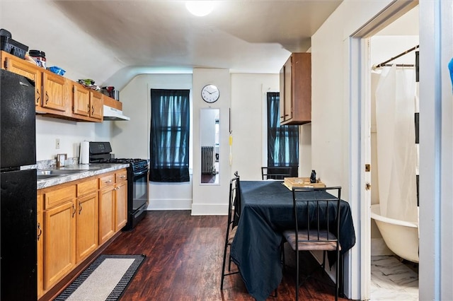 kitchen with under cabinet range hood, dark wood finished floors, vaulted ceiling, black appliances, and light countertops