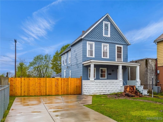 view of front of property with a porch, fence, a front lawn, and central air condition unit