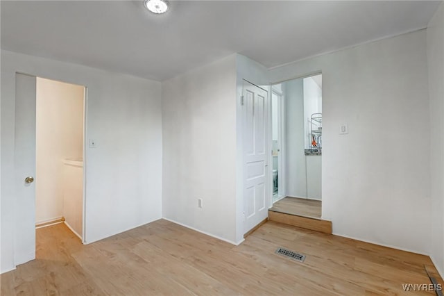 spare room featuring light wood finished floors and visible vents