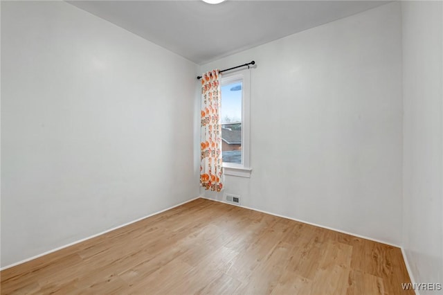 unfurnished room featuring visible vents, wood finished floors, and baseboards