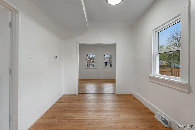 corridor with light wood-type flooring, a healthy amount of sunlight, and visible vents