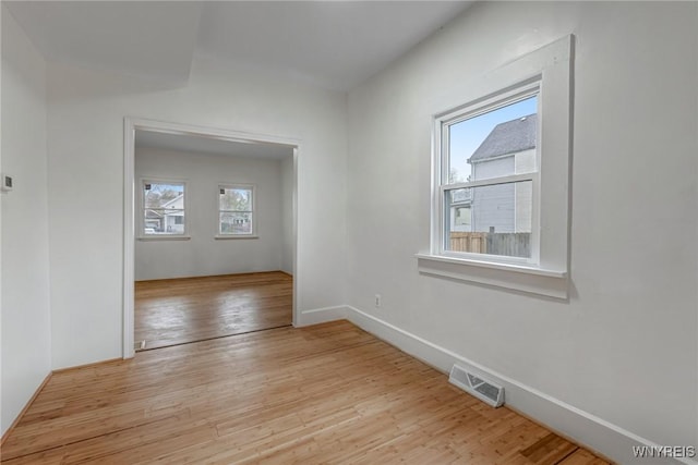 spare room with light wood finished floors, baseboards, and visible vents