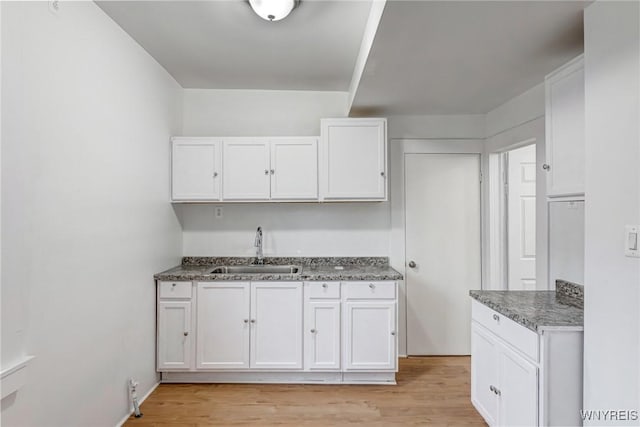 kitchen featuring light wood-style flooring, white cabinets, and a sink