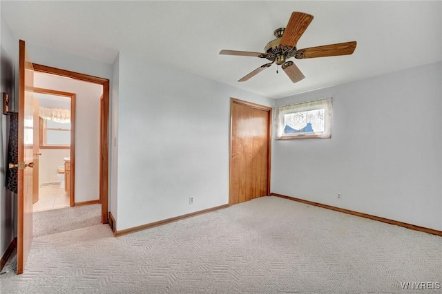 spare room featuring light colored carpet, baseboards, and ceiling fan