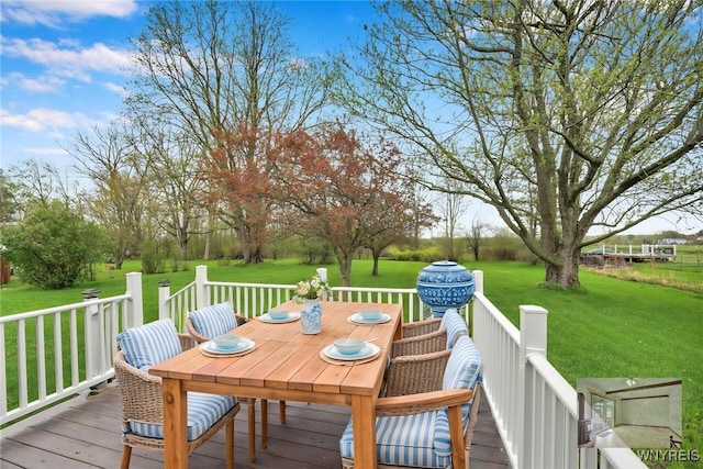 wooden terrace featuring outdoor dining area and a lawn