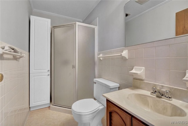 bathroom featuring a stall shower, tile walls, vanity, and crown molding
