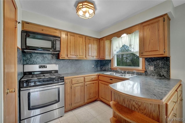 kitchen featuring a sink, black microwave, backsplash, light tile patterned floors, and stainless steel gas range
