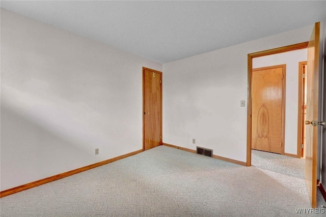 empty room featuring carpet flooring, baseboards, and visible vents