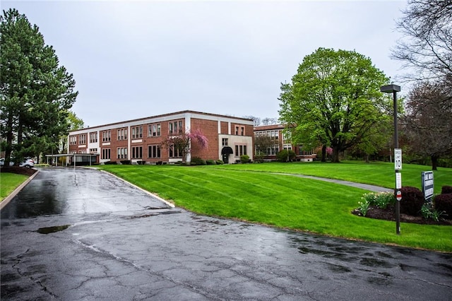 view of property's community featuring a lawn and aphalt driveway