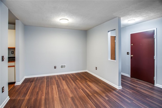 unfurnished room featuring dark wood finished floors, visible vents, baseboards, and a textured ceiling