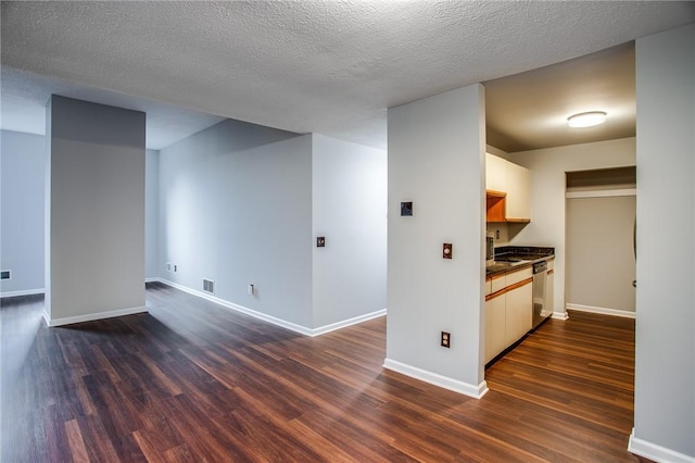 interior space featuring visible vents, dishwasher, dark wood-style floors, baseboards, and dark countertops