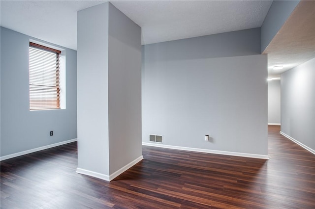 empty room with baseboards, dark wood finished floors, and visible vents