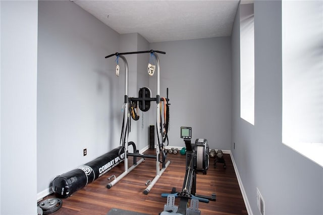workout area featuring baseboards, visible vents, and wood finished floors