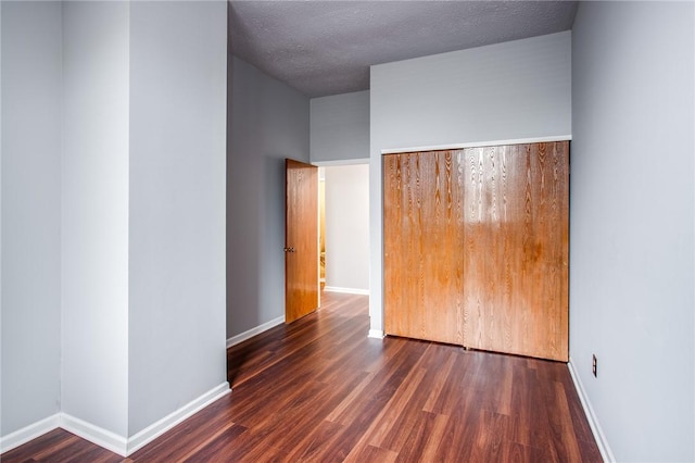 spare room with a textured ceiling, baseboards, and wood finished floors