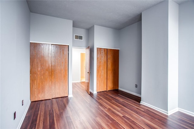 unfurnished bedroom featuring baseboards, dark wood-style floors, and visible vents