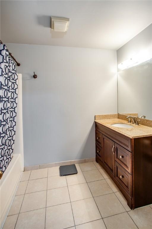 bathroom with vanity, baseboards, shower / bath combo, and tile patterned flooring