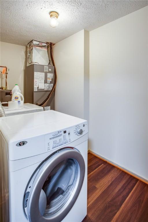washroom with separate washer and dryer, laundry area, a textured ceiling, and wood finished floors
