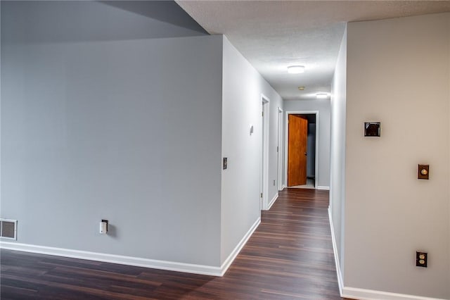 corridor featuring baseboards, visible vents, and dark wood finished floors