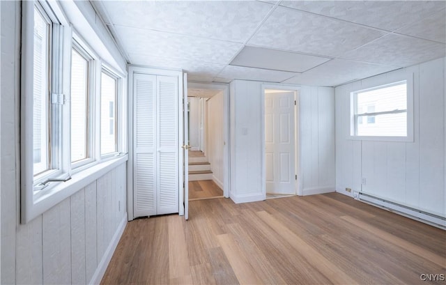 unfurnished bedroom with baseboards, a baseboard radiator, and light wood-type flooring