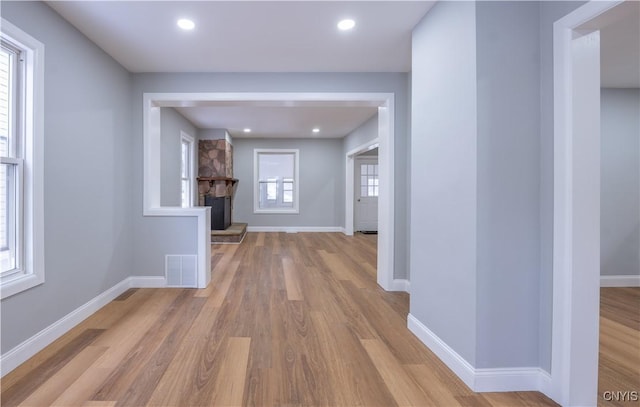 corridor featuring visible vents, light wood-style flooring, and baseboards
