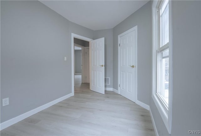 unfurnished bedroom with visible vents, light wood-style flooring, and baseboards