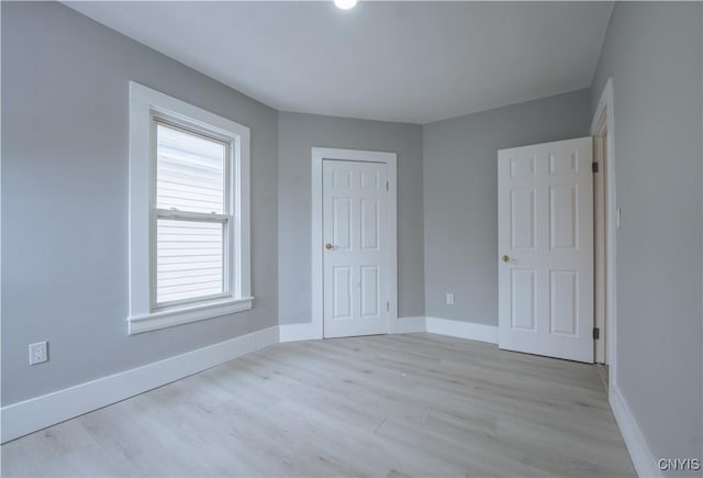 unfurnished bedroom featuring a closet, light wood-style floors, and baseboards