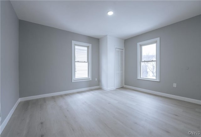 unfurnished bedroom with baseboards, a closet, and light wood-style flooring