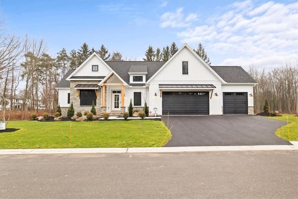947 Timberland Ct, Webster, NY 14580 - modern farmhouse with stone siding, asphalt driveway, a standing seam roof, a front yard, and a garage