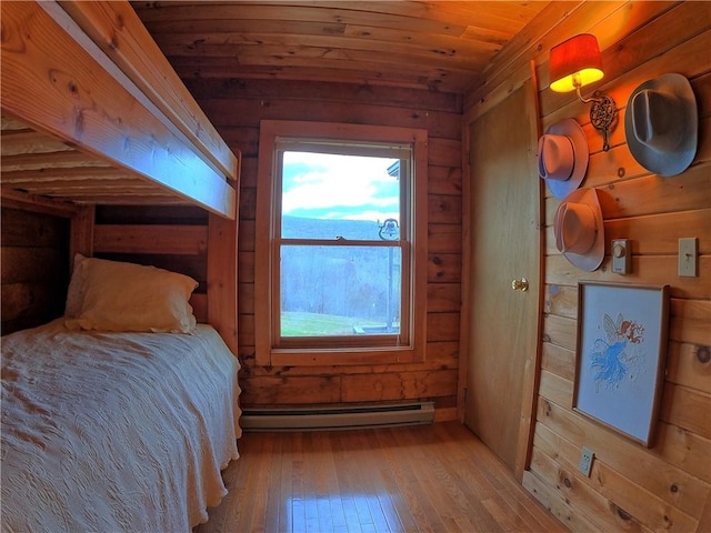 bedroom with wooden ceiling, wood walls, a baseboard radiator, and hardwood / wood-style flooring