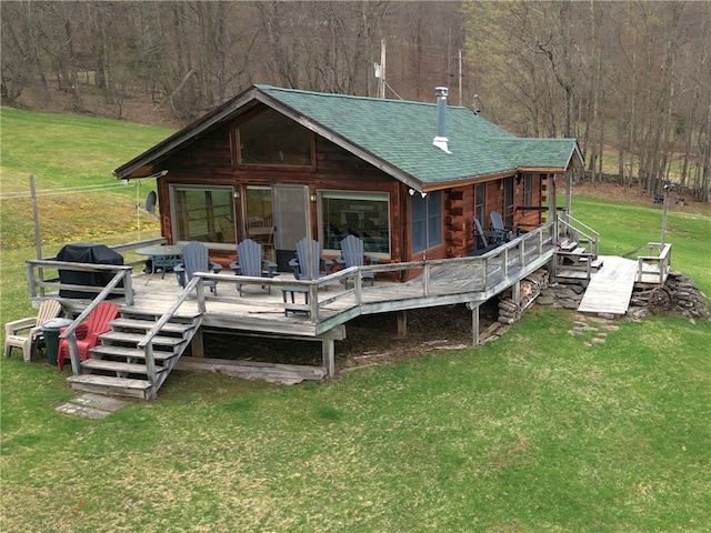back of house with a wooded view, log siding, a wooden deck, a yard, and roof with shingles