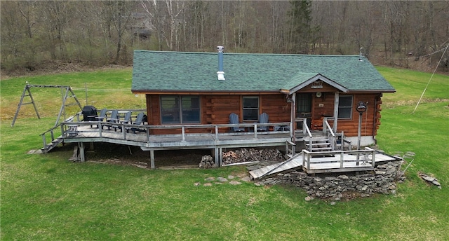 back of property with a lawn, a forest view, roof with shingles, and log siding
