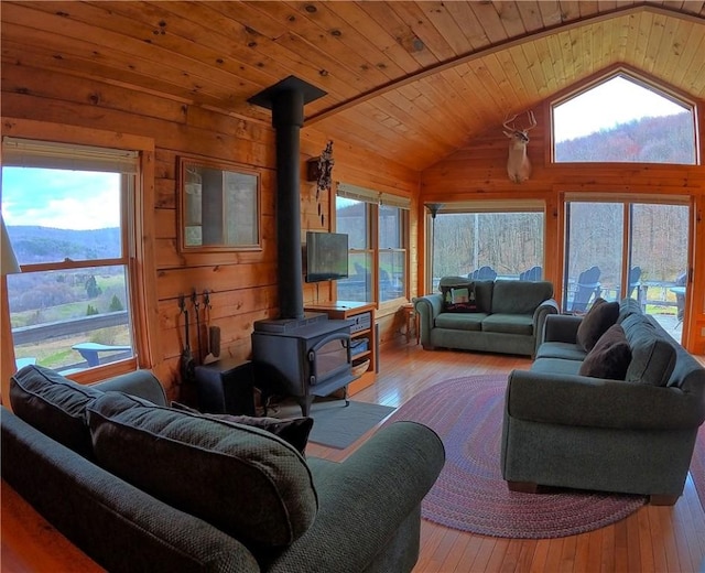 living room with wood-type flooring, wood walls, a wood stove, wooden ceiling, and lofted ceiling