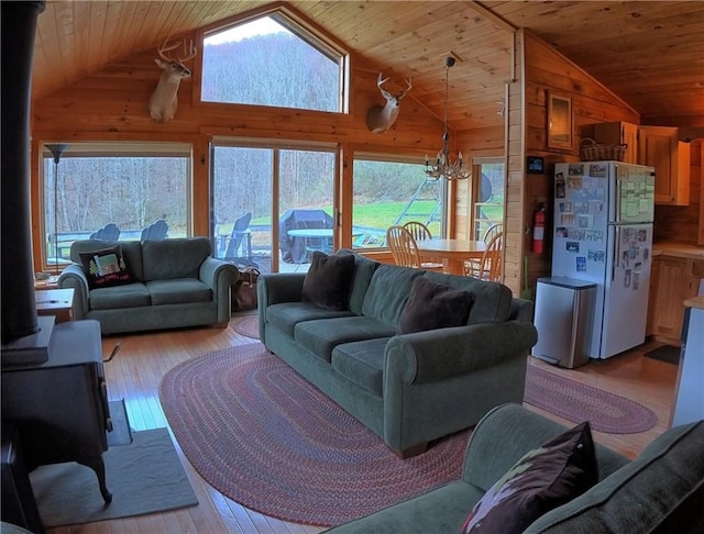 living room featuring a chandelier, vaulted ceiling, wood walls, and light wood-style flooring