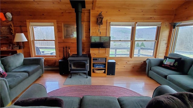 living room with light wood finished floors, wood walls, and a wood stove
