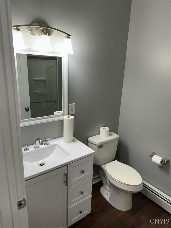 bathroom with vanity, toilet, wood finished floors, and a baseboard radiator