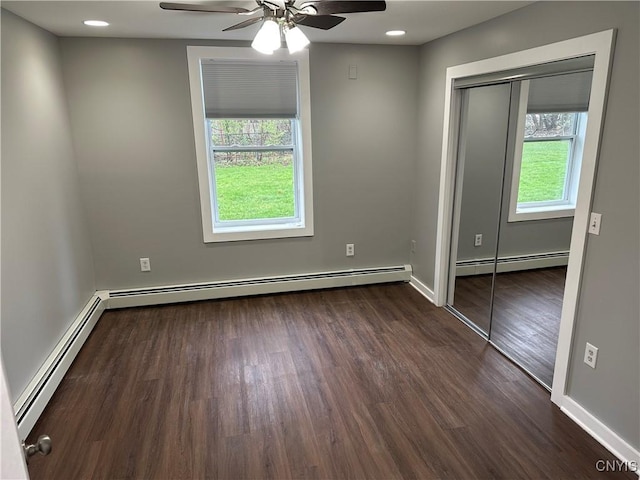 unfurnished bedroom featuring multiple windows and a baseboard heating unit