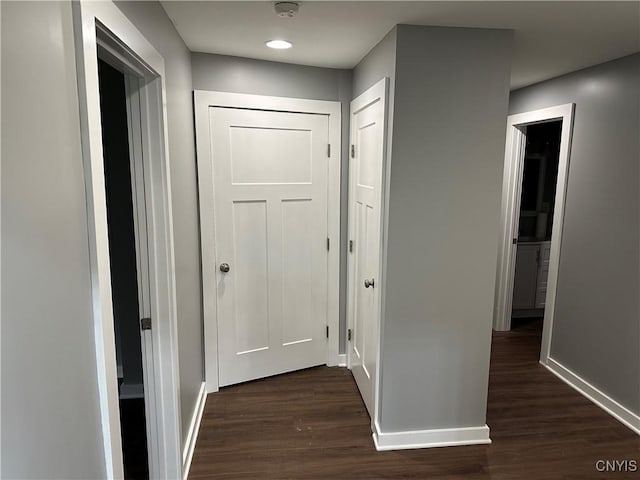corridor featuring baseboards and dark wood finished floors
