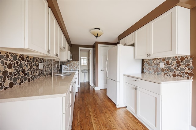 kitchen featuring light wood-style flooring, white cabinetry, stainless steel microwave, and backsplash