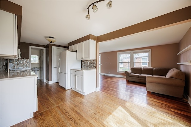 kitchen featuring freestanding refrigerator, tasteful backsplash, white cabinets, light wood finished floors, and open floor plan