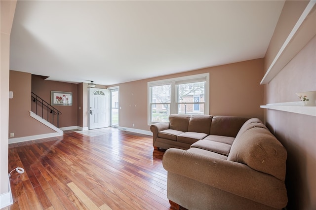 living room featuring hardwood / wood-style flooring, stairs, and baseboards