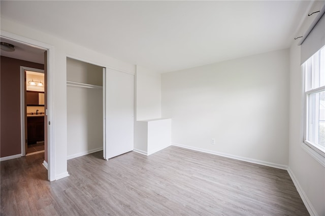 unfurnished bedroom with wood finished floors, a closet, and baseboards
