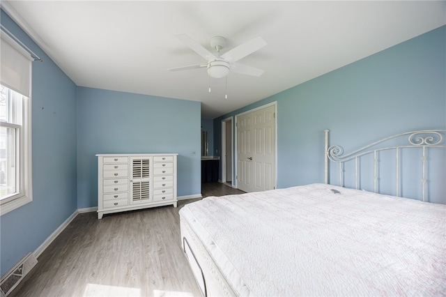 bedroom with wood finished floors, multiple windows, ceiling fan, and baseboards