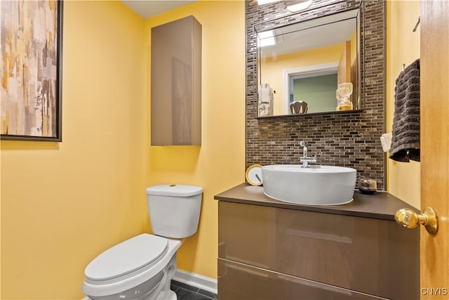 half bathroom featuring backsplash, toilet, vanity, baseboards, and tile patterned flooring
