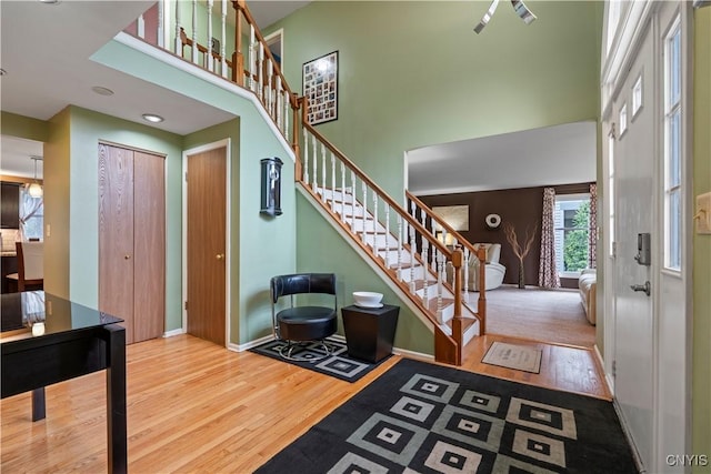 entrance foyer with a towering ceiling, wood finished floors, stairway, and baseboards