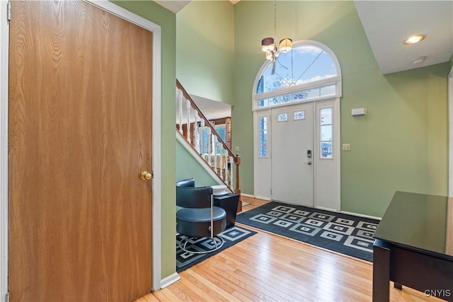 foyer entrance with hardwood / wood-style flooring, stairs, a high ceiling, and a chandelier