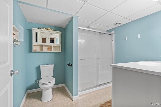 bathroom with a stall shower, toilet, baseboards, tile patterned floors, and a drop ceiling