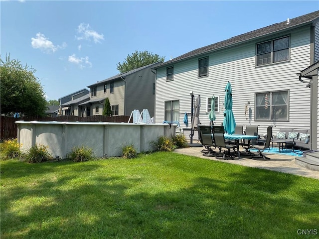 rear view of house with a lawn, an outdoor pool, and a patio area
