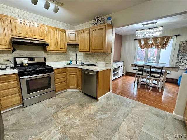 107 Birchwood Ln, Frankfort, NY 13340 - kitchen featuring under cabinet range hood, a sink, light countertops, tasteful backsplash, and appliances with stainless steel finishes
