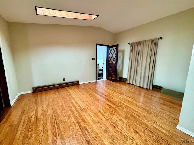 107 Birchwood Ln, Frankfort, NY 13340 - empty room featuring light wood finished floors, baseboards, vaulted ceiling with skylight, and a baseboard heating unit