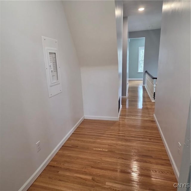 corridor featuring baseboards, an upstairs landing, and wood finished floors